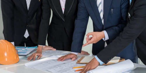 Cropped image of investors analyzing construction plan of building