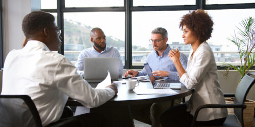 Multi-Cultural Business Team Meeting Collaborating Sitting Around Table In Modern Office Together